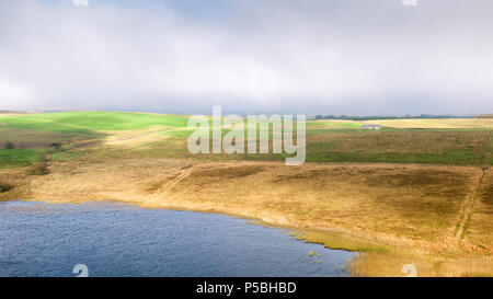 Vista panoramica su una rupe di Lough verso terreni agricoli circostanti in Northumberland National Park in una nebbiosa mattina, Hexham, Northumberland, Regno Unito. Foto Stock