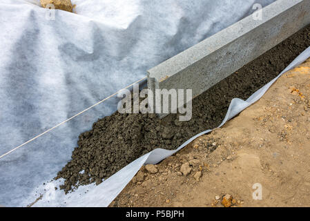 Impostazione di restrizioni di bordo acquistare mettendo cordolo di confine pietre in massa di calcestruzzo umido Foto Stock