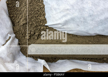 Impostazione di restrizioni di bordo acquistare mettendo cordolo di confine pietre in massa di calcestruzzo umido Foto Stock