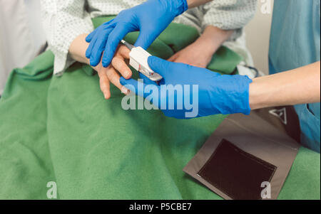 Infermiere paziente di collegamento al dispositivo di monitoraggio nella stanza di ospedale Foto Stock