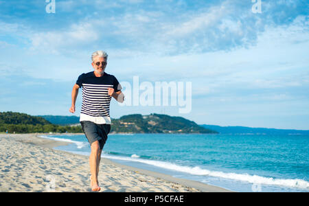 Senior uomo correre sulla spiaggia, uno stile di vita sano Foto Stock