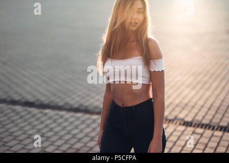 Ritratto di giovane e bella donna in abiti casual in strada. Vestito in Maglia Rosa e pantaloni. Primavera, estate concetto. Tempo di relax. Ragazza con Foto Stock