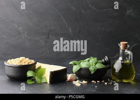 Foglie di basilico e parmigiano e altri pesto ingredienti su nero Foto Stock