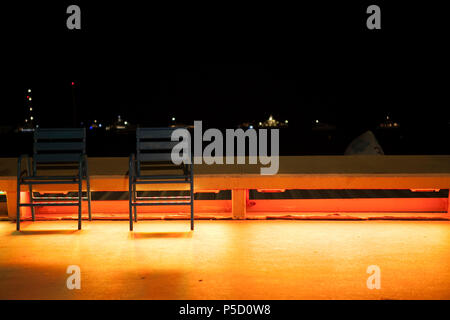 Zwei öffentliche, unbesetzte Stühle in benzina, die indirektes Licht von hinten bekommen auf der la Croisette a Cannes, Frankreich. Foto Stock