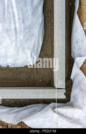 Impostazione di restrizioni di bordo acquistare mettendo cordolo di confine pietre in massa di calcestruzzo umido Foto Stock