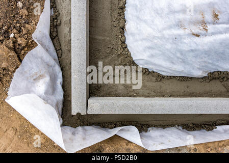 Impostazione di restrizioni di bordo acquistare mettendo cordolo di confine pietre in massa di calcestruzzo umido Foto Stock