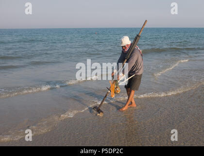 L'uomo la rastrellatura per clam conchiglie sulla spiaggia, Prachuap Khiri Khan Provincia, Hua Hin, Thailandia, in Asia. Foto Stock