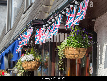 Una fila di Union Jack Flag e due cestelli appesi al di fuori di una casa pubblica a Bowness-On-Windermere Foto Stock