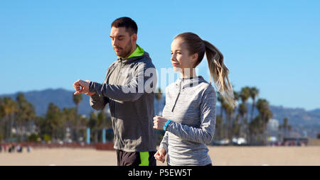 Giovane con fitness trackers correndo all'aperto Foto Stock