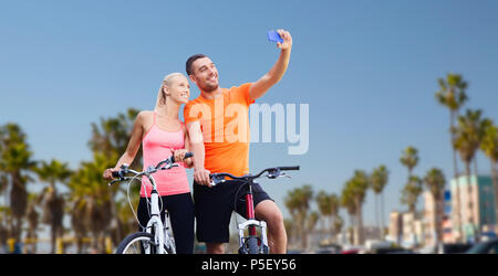 Giovane con le biciclette tenendo selfie tramite smartphone Foto Stock