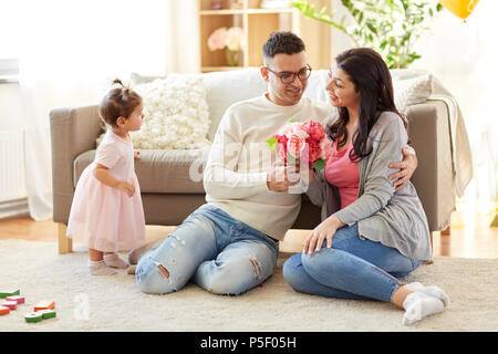 Felice marito dando fiori a sua moglie a casa Foto Stock