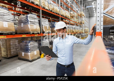 Imprenditore nel casco con appunti a magazzino Foto Stock