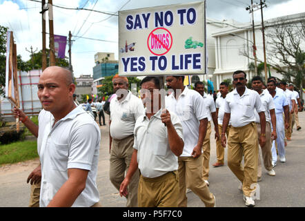 I membri della polizia indiana ha marciato con manifesti durante il rally. Gli Stati indiani di forze paramilitari e la polizia indiana sono a piedi e a cavallo di biciclette in un rally, in occasione della Giornata Internazionale contro l abuso e il traffico illecito di Agartala, capitale del nord-est stato di Tripura, India. Foto Stock
