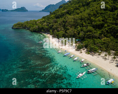 Antenna fuco vista della Banca tradizionali barche e barriera corallina che circonda una pittoresca spiaggia sabbiosa tropicale (7 Commando Beach, El Nido) Foto Stock