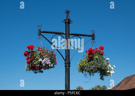 Close-up di cestelli appesi piantati con fiori colorati contro un cielo blu a Stockbridge Town Center, Hampshire, Regno Unito Foto Stock