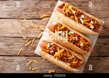 Tradizionale American chili hot dogs con il formaggio cheddar e cipolla e salsa piccante closeup sul tavolo. parte superiore orizzontale vista da sopra Foto Stock