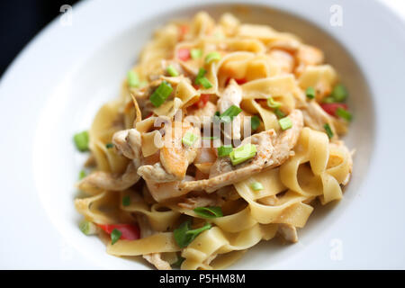 Pasta con pollo e verdure sulla piastra bianca. Tavolo in legno sfondo. Chiudere il cibo foto. Foto Stock