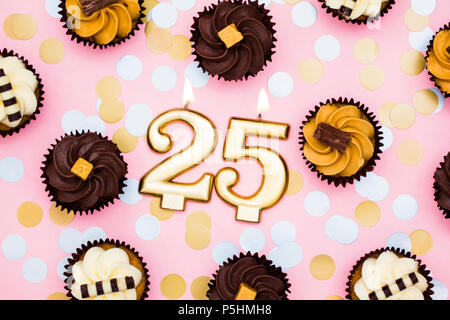 Numero 25 oro candela con tortine contro un pastello sfondo rosa Foto Stock