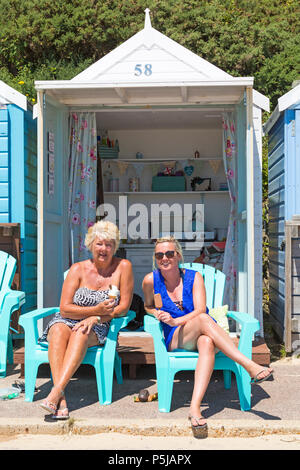 Bournemouth, Dorset, Regno Unito. 27 giugno 2018. Tempo nel Regno Unito: Gli amanti del sole si dirigono verso le spiagge di Bournemouth in un'altra bella e calda giornata di sole con cieli blu e sole ininterrotti. Una piacevole brezza di raffreddamento oggi rende il calore più sopportabile. Tempo per i gelati - due donne godendo il sole mangiare gelati seduti fuori dal rifugio sulla spiaggia. Foto Stock