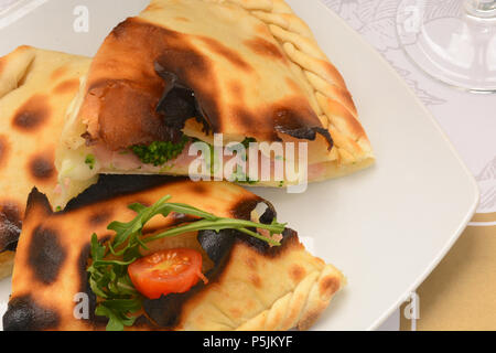 Close-up chiusa la pizza italiana calzone sulla piastra bianca Foto Stock