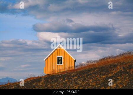 Bellissima vista del tradizionale giallo cabin prati e dark moody nubi in un giorno di estate in Islanda Foto Stock