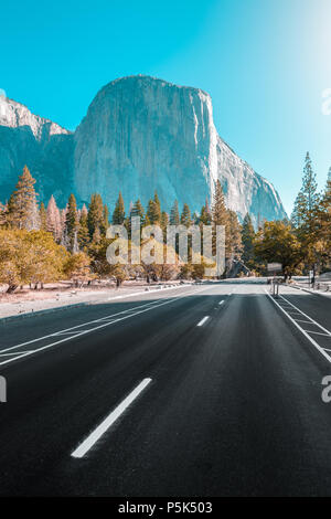 Famoso El Capitan picco di montagna con la strada che attraversa il Parco Nazionale di Yosemite Valley in beautiful Golden. La luce del mattino al sorgere del sole in estate, CALIFORNIA, STATI UNITI D'AMERICA Foto Stock