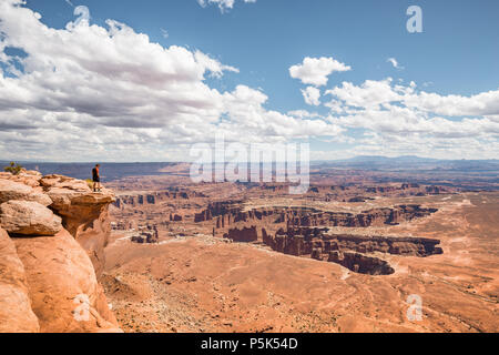 Un maschio di un escursionista è in piedi sul bordo di una scogliera godendo di una drammatica si affacciano di paesaggio panoramico nel bellissimo Parco Nazionale di Canyonlands, Utah, Stati Uniti d'America Foto Stock