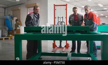 I lavoratori di sesso maschile con produzione di macchine a CNC la pulizia dello spazio di lavoro Foto Stock