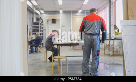 I lavoratori di sesso maschile con produzione di macchine a CNC la pulizia dello spazio di lavoro Foto Stock