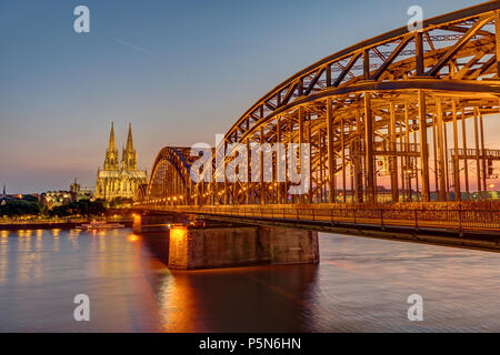 Gli illuminati Hohenzollern ponte con la famosa cattedrale di Colonia dopo il tramonto Foto Stock