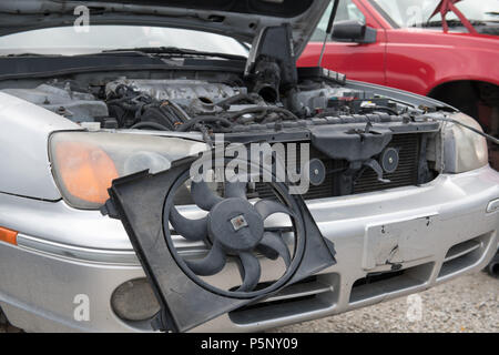 Il vano motore del relitto di una vettura con il fuoco selettivo sulla ventola del radiatore appendere fuori della parte anteriore di esso Foto Stock