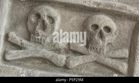 Antico casale in pietra con cranio crossbones. Scultura antica. Ideale per i concetti e gli sfondi. Foto Stock