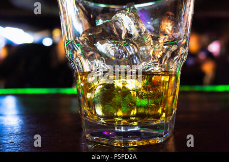 Bicchiere di whiskey con ghiaccio si erge sulla barra. Close-up foto con morbida messa a fuoco selettiva Foto Stock