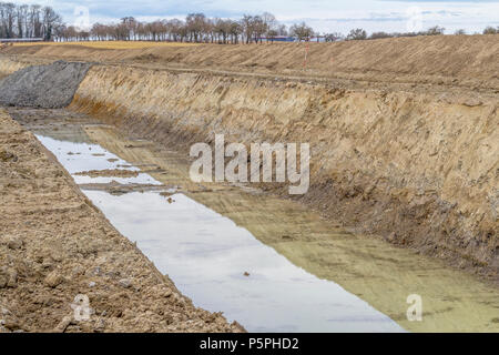 Sito in costruzione tra una grande trincea con un sacco di terra e terriccio Foto Stock