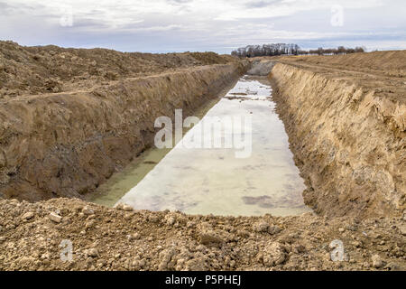 Sito in costruzione tra una grande trincea con un sacco di terra e terriccio Foto Stock