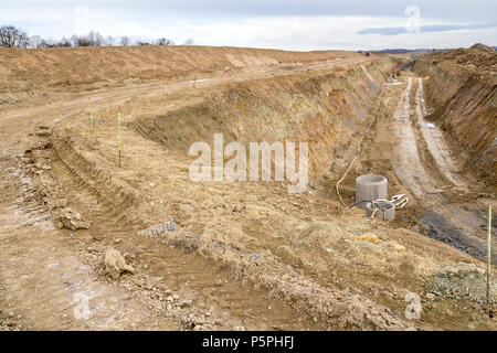 Sito in costruzione tra una grande trincea con un sacco di terra e terriccio Foto Stock