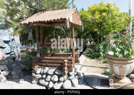 Antico pozzo artesiano e tetto in legno e puleggia di legno. Foto Stock