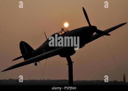 Hawker Hurricane replica custode di gate a North Weald airfield, ex RAF Royal Air Force Battle of Britain Seconda Guerra Mondiale airbase. Crepuscolo. Tramonto Foto Stock