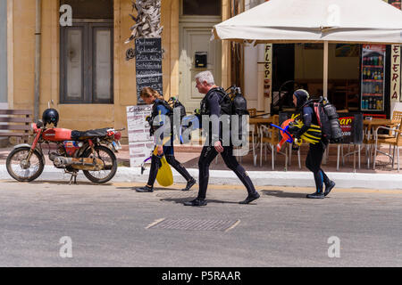 Tre subacquei che indossa la piena attrezzatura subacquea a piedi giù per una strada a Gozo, Malta Foto Stock