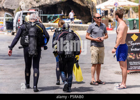 Tre subacquei che indossa la piena attrezzatura subacquea a piedi giù per una strada a Gozo, Malta Foto Stock