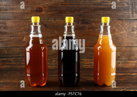 Diverse varietà di birra artigianale in bottiglie di plastica su un sfondo di legno Foto Stock