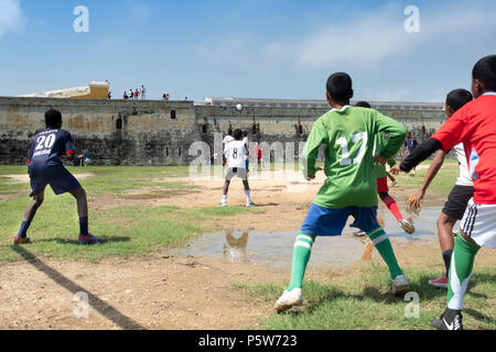 Colombia, Cartagena, i bambini locali che giocano a calcio vicino al vecchio muro fortificato della città coloniale spagnola. Foto Stock