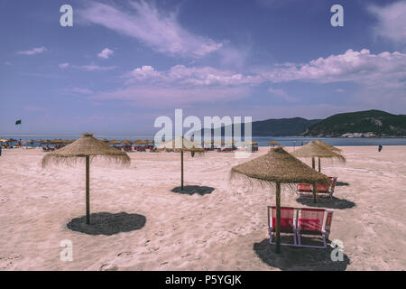 Giugno 21st, 2018 Bico das Lulas Beach, Troia, Portogallo - ombrelloni di paglia e sedie ad una spiaggia di sabbia Foto Stock