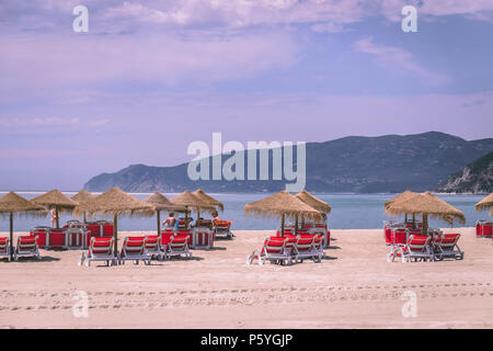 Giugno 21st, 2018 Bico das Lulas Beach, Troia, Portogallo - ombrelloni di paglia e sedie ad una spiaggia di sabbia Foto Stock