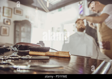 Accessori per il taglio sul tavolo in un barbiere e parrucchiere lavora in background. Foto in stile vintage Foto Stock