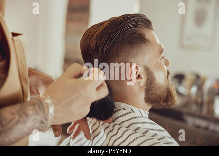 Barbiere scuote capello fuori dal client il collo. Foto in stile vintage Foto Stock