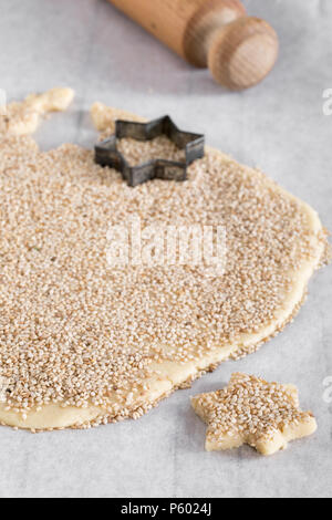 Il taglio a forma di stella biscotti di pasta cosparso con semi di sesamo su della carta da cucina. Foto Stock