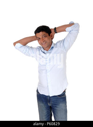 Un sorridenti uomo asiatico in piedi in jeans e una leggera maglietta blu con le mani dietro la testa, isolato per sfondo bianco Foto Stock