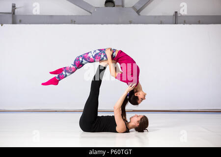 Il tema è lo sport e uno stile di vita sano. Le acrobazie e la superficie coltivata. Due persone di giovani donne con una bella figura a fare gli esercizi a coppie, il lavoro di squadra in un Foto Stock