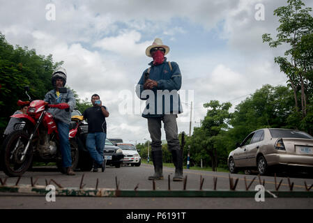 27 giugno 2018, Nicaragua, Chontales: un manifestante mascherato sorge su un chiodo blocco contro il governo. I cittadini e i lavoratori agricoli bloccato una strada di campagna da Managua a chontales. I blocchi sono parte delle proteste contro il governo di Daniel Ortega. La situazione in Nicaragua non ha calmata dalla metà di aprile. L'autoritario Presidente Ortega ha voluto spingere attraverso una riforma sociale, ma il pubblico in generale contrari. Fin dal momento in cui le masse sono state per le strade chiedendo le dimissioni del presidente e di sua moglie, Vice Presidente Murillo. Foto: Carlos Herrera/dpa Foto Stock